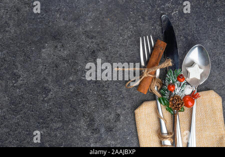 Christmas table place setting, cutlery in burlap bag with festive decorations star, cinnamon stick, pinecone with snow, berries, branch. Christmas Stock Photo