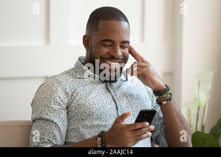 Smiling biracial man relax texting on smartphone Stock Photo