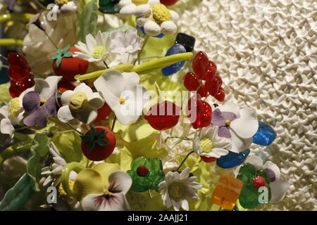 colour image showing a varied selection of brightly coloured man made table decorations in the form of flowers and beads against a white lattice Stock Photo