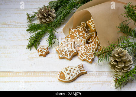 Homemade gingerbread cookies for Christmas in a paper bag, fir branches and pine cones on a white painted wooden table, copy space, selected focus Stock Photo