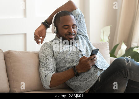 Smiling biracial man listen to music in headphones at home Stock Photo