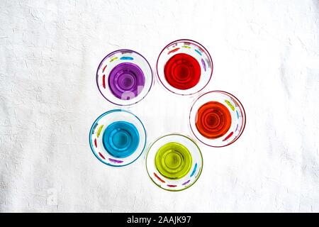 Colorful drinking glasses on white background. Round circuls red, orange, blue green purple neon lights. Stock Photo