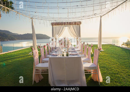 Dinner table with flower decoration in Wedding ceremony in the sunset time. Stock Photo