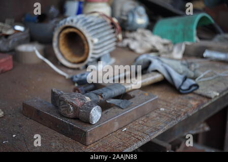 Old hammer with a wooden handle wrapped in electrical tape on a joiner's desk. Garage Tools Stock Photo