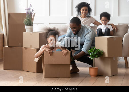 African father riding daughter sitting inside of big carton box Stock Photo