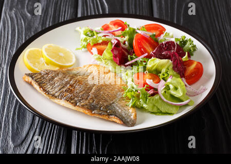 Baked dorado (sea bream) fillet served with fresh vegetable salad close-up on a plate on the table horizontal Stock Photo