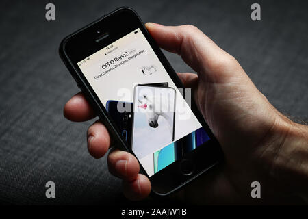 A man looking at the OPPO website on his mobile phone Stock Photo