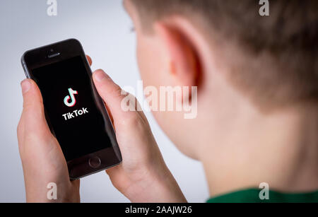 A Teenage boy using the TikTok app on a mobile phone Stock Photo