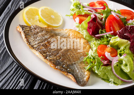 Fried gilt-head fish fillet with a side dish of vegetable salad close-up on a plate on the table. horizontal Stock Photo