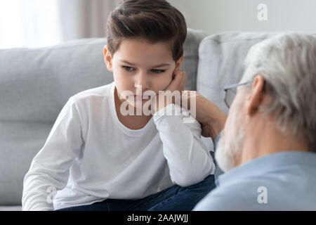 Caring grandfather calming, talking with upset little grandson Stock Photo