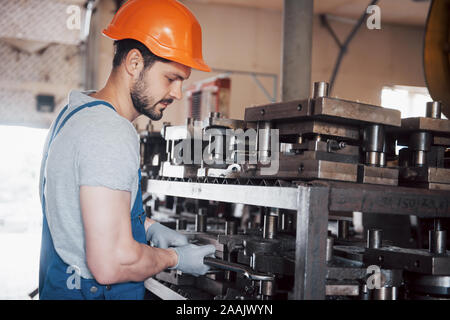 Portrait of a young worker in a hard hat at a large metalworking plant. The engineer serves the machines and manufactures parts for gas equipment Stock Photo