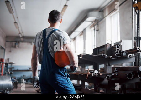 Portrait of a young worker in a hard hat at a large waste recycling factory. The engineer monitors the work of machines and other equipment Stock Photo