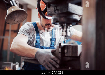 Portrait of a young worker in a hard hat at a large metalworking plant. The engineer serves the machines and manufactures parts for gas equipment Stock Photo