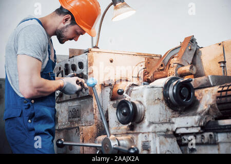 Portrait of a young worker in a hard hat at a large metalworking plant. The engineer serves the machines and manufactures parts for gas equipment Stock Photo