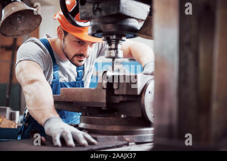 Portrait of a young worker in a hard hat at a large waste recycling factory. The engineer monitors the work of machines and other equipment Stock Photo