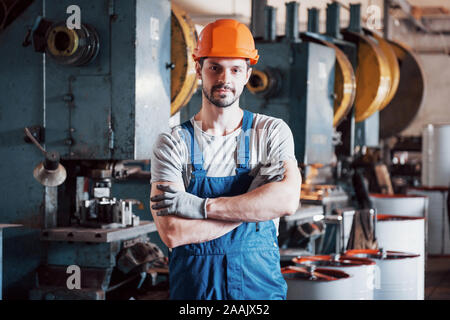 Portrait of a young worker in a hard hat at a large metalworking plant. Shiftman on the warehouse of finished products Stock Photo