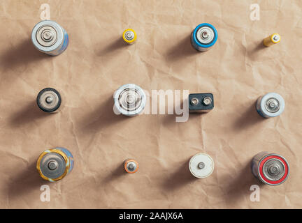 Used Alkaline batteries of different types (C AA AAA D 9V) on wrinkled recycled paper sorted for recycling - toxic waste and environmental issues back Stock Photo