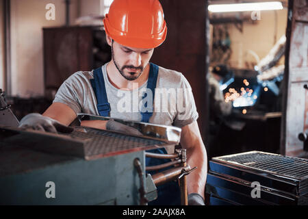 Portrait of a young worker in a hard hat at a large metalworking plant. The engineer serves the machines and manufactures parts for gas equipment Stock Photo