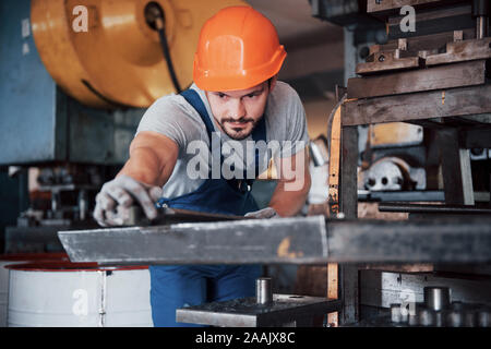Portrait of a young worker in a hard hat at a large metalworking plant. The engineer serves the machines and manufactures parts for gas equipment Stock Photo