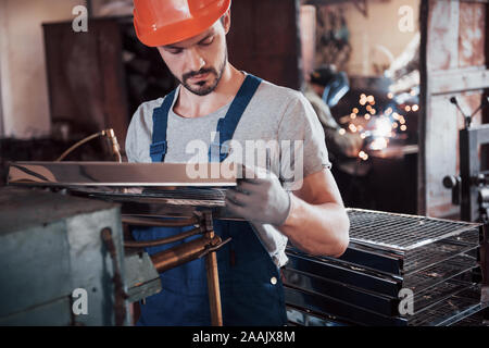 Portrait of a young worker in a hard hat at a large waste recycling factory. The engineer monitors the work of machines and other equipment Stock Photo