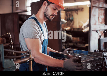 Portrait of a young worker in a hard hat at a large metalworking plant. The engineer serves the machines and manufactures parts for gas equipment Stock Photo