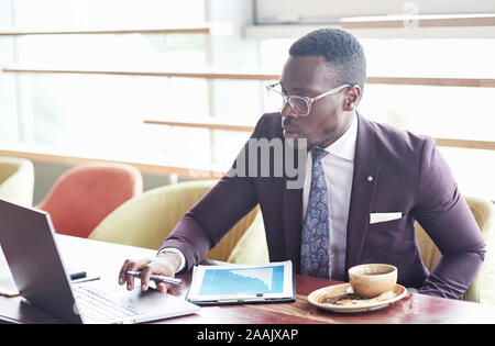 A beautiful stylish African American businesswoman wearing a suit uses his laptop while working. Stock Photo