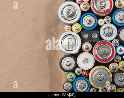 Used Alkaline batteries of different types (C AA AAA D 9V) on wrinkled recycled paper sorted for recycling - toxic waste and environmental issues back Stock Photo