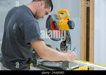 Carpenter cutting wooden trim board on with circular saw. Woodworker works on remodeling home Stock Photo