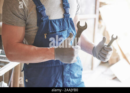 Master in working form and gloves with a key in his hands. Stock Photo