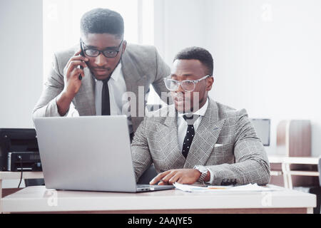 Modern businessman at work. Two confident business people in formalwear discussing something and look at the laptop monitor Stock Photo