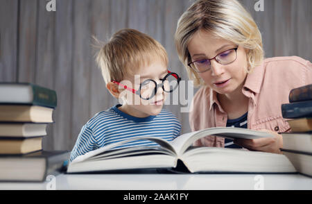 five years old child reading a book at home with mother Stock Photo