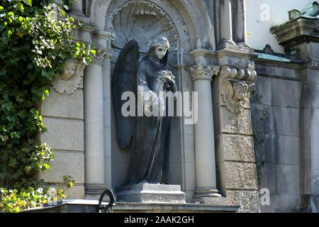 Sculpture of an Angel with flowers (roses) in her hand on a family tomb / crypt at the cemetery at Suedstern Stock Photo