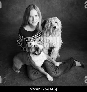 Studio portrait of woman with English Bulldog and Mini Golden Doodle Stock Photo