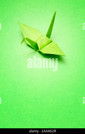 green origami bird on green background Stock Photo