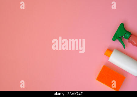 Cleaning products on pink background. Detergents in plastic bottles, spray and sponge. Housekeeping chores. Top view. Copy space. Stock Photo