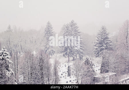 Top view on city cemetery in Banska Bystrica, Slovakia in heavy snowing day. Graveyard in snow. Blizzard in the city. Stock Photo