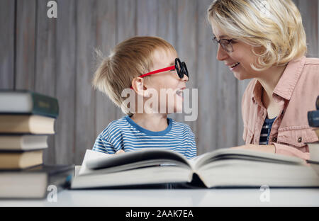 five years old child reading a book at home with mother Stock Photo