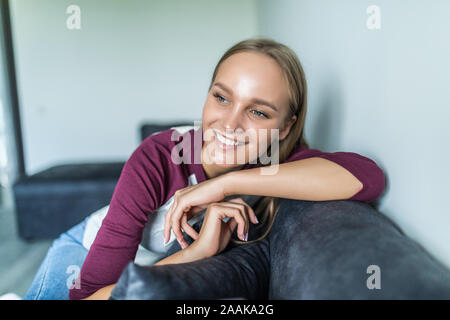 Happy woman relaxing on comfortable soft sofa enjoying stress free weekend at home Stock Photo