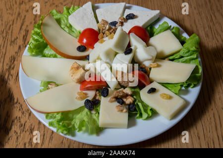 Top view . Cheese plate with different kinds of cheese with thyme walnuts and tomatoes . Cheese plates served with bruised on a wooden board. Stock Photo