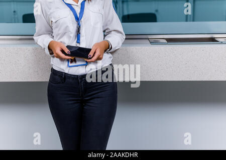 Security woman holding a smartphone in her hands and standing at the info desk Stock Photo