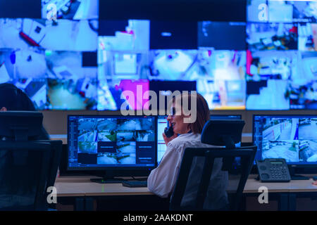 Team working on the System Control Room, Technical Operator Works at His Workstation with Multiple Displays, Security guards working on multiple monit Stock Photo