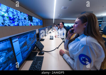 Technical Operator Works at His Workstation with Multiple Displays while talking on the phone, Security guards working on multiple monitors. Stock Photo
