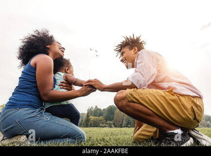 Happy African family having fun in public park - Mother, father and daughter enjoying together during a weekend sunny day outdoor Stock Photo