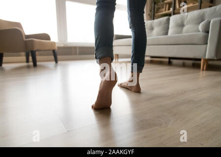 Close up of woman walking barefoot on warm wooden floor Stock Photo