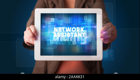 Young business person working on tablet and shows the inscription: NETWORK ASSISTANT Stock Photo