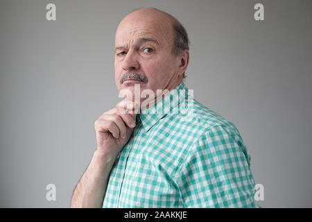 Senior bald man with a double chin looking sadly at camera. Studio shot Stock Photo