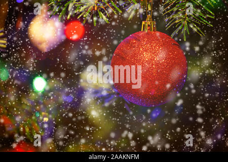 Closeup of red bauble hanging from a decorated Christmas tree. Christmas background - baubles and branch of spruce tree Stock Photo