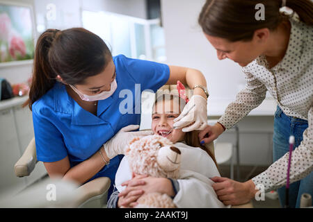 Little smiling girl visiting dentist .Dentist examining tooth patient in ambulant. Stock Photo