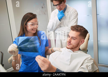 Smiling Doctor dentist showing young patient's teeth on X-ray Stock Photo