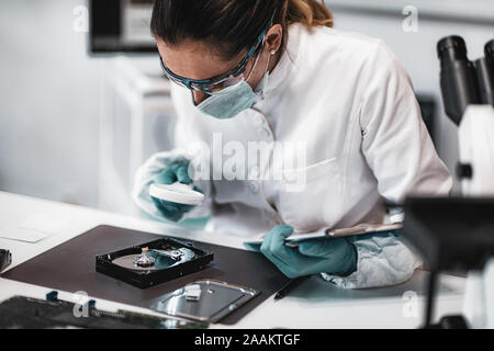 Forensic science technician examining computer hard drive Stock 